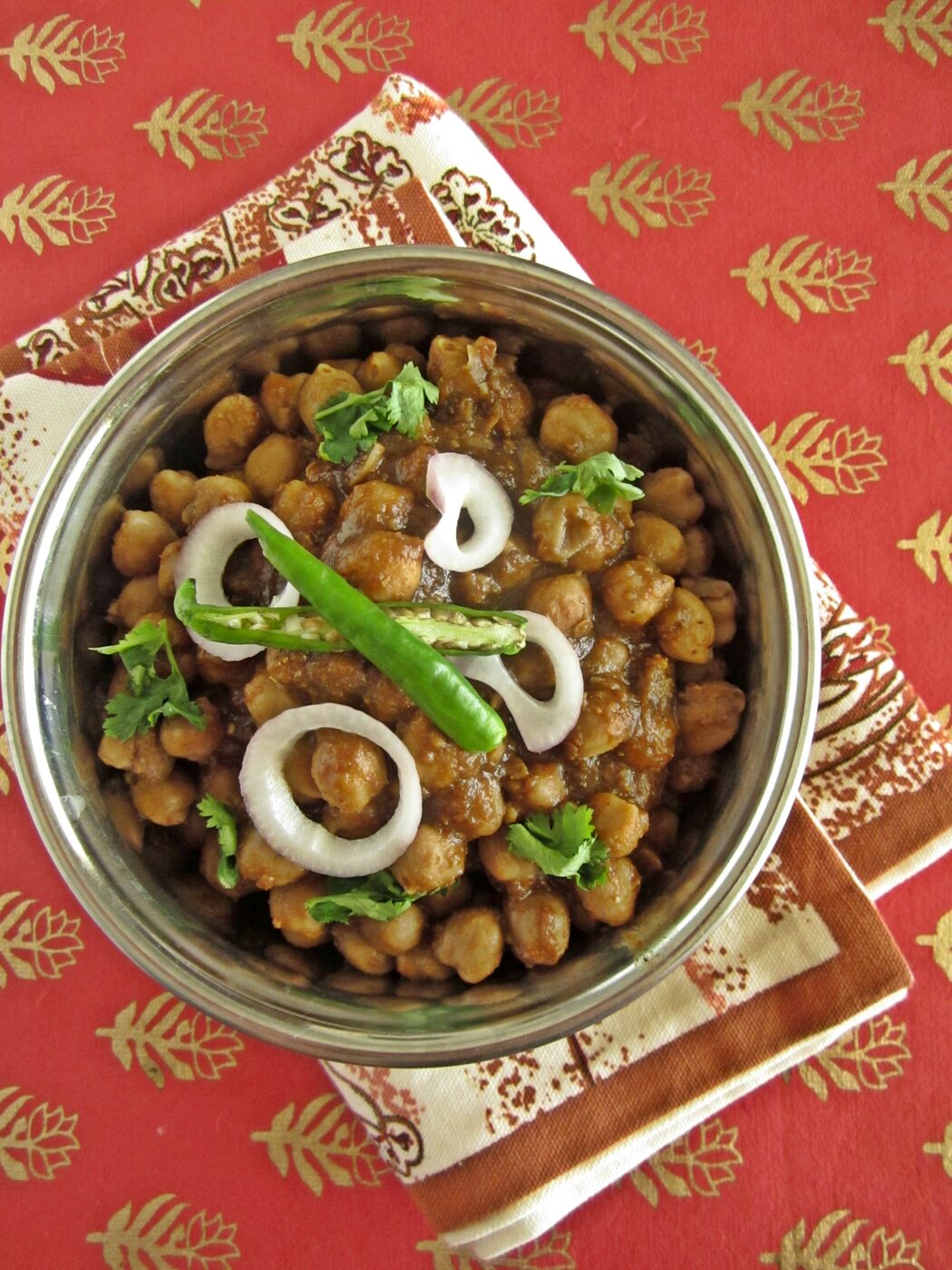 Chole (chickpea curry) garnished with onion and green chilli